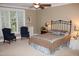 Spacious bedroom with a large bed, two chairs, and window with blinds at 7115 Laurel Point Dr, Gibsonville, NC 27249