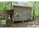 Rustic log cabin nestled in a wooded setting, featuring a porch and steps at 7115 Laurel Point Dr, Gibsonville, NC 27249