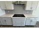 Well-lit kitchen featuring white cabinets, drawers, backsplash, and a stainless steel vent hood at 85 N Stagecoach Dr, Wendell, NC 27591