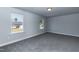 A carpeted room with neutral-toned walls is illuminated by two windows offering natural lighting at 128 High Hampton Way, Fuquay Varina, NC 27526