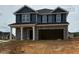 Two-story home featuring gray stone and siding, attached two-car garage, and a covered front porch with white pillars at 128 High Hampton Way, Fuquay Varina, NC 27526