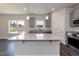 Open-concept kitchen with island, stainless steel appliances, and gray cabinets, seamlessly flowing into the living area at 128 High Hampton Way, Fuquay Varina, NC 27526