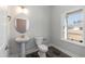 Bright powder room with pedestal sink, decorative mirror, and black tile flooring, next to a window at 128 High Hampton Way, Fuquay Varina, NC 27526