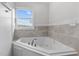 Corner soaking tub with tile surround and natural light from the window at 1696 James Winston Rd, Oxford, NC 27565