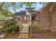 Brick home featuring a wooden deck with steps leading down to a garden area with purple flowering bushes at 801 Williamsboro St, Oxford, NC 27565