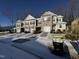 Row of three two-story townhouses with attached garages, snowy landscaping, and wooded background at 133 Walking Path Pl, Hillsborough, NC 27278