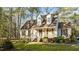 Inviting two-story home with a classic design, red shutters, and a covered front porch nestled among tall trees at 1909 Pearces Rd, Zebulon, NC 27597