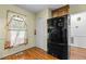 Bright kitchen featuring a black stainless steel refrigerator, hardwood floors, and a window with patterned curtains at 1909 Pearces Rd, Zebulon, NC 27597