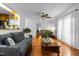 Spacious living room features hardwood floors, gray sofa, ceiling fan, curtains, and view of other living areas at 1909 Pearces Rd, Zebulon, NC 27597