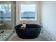 Black freestanding bathtub with gold fixtures and large window at 2011 Angier Ave, Durham, NC 27703