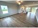 Bright, open-concept living room with wood floors, large windows, and a modern kitchen in the background at 25 Calabria Ct, Franklinton, NC 27525