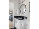 Modern bathroom boasts a black granite countertop, white vanity, and round mirror, exuding sophistication at 2721 Sanctuary Woods Ln, Raleigh, NC 27606