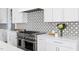 Kitchen featuring stainless steel range and white cabinets, black and white tile backsplash at 2721 Sanctuary Woods Ln, Raleigh, NC 27606
