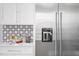 Modern kitchen features stainless steel refrigerator, white cabinetry and backsplash with marble countertops at 2721 Sanctuary Woods Ln, Raleigh, NC 27606