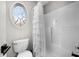 Bathroom featuring oval window, toilet, and bathtub with white tile surround at 3020 Imperial Oaks Dr, Raleigh, NC 27614