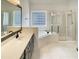 A bright bathroom boasts a bathtub and walk-in shower with a sink and vanity at 408 Froyle Ct, Rolesville, NC 27571