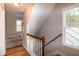 View of home staircase with white spindles, wood railing, and two windows for natural light at 496 Omaha Dr, Broadway, NC 27505