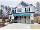 Two-story home with white siding, blue accents, and a modern garage door at 5112 N River Sand Trl, Raleigh, NC 27604