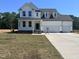 Charming two-story home featuring a welcoming front porch and a three car attached garage at 92 Frost Meadow Way, Lillington, NC 27546