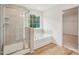 Bright bathroom featuring a glass shower, soaking tub, and a window at 92 Frost Meadow Way, Lillington, NC 27546