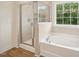 Bright bathroom featuring a glass shower, soaking tub, and a window at 92 Frost Meadow Way, Lillington, NC 27546