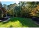 Grassy backyard bordered by mature trees and professional landscaping at 11201 Jonas Ridge Ln, Raleigh, NC 27613