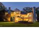 Illuminated backyard with balconies, a spiral staircase, and manicured landscaping at twilight at 11201 Jonas Ridge Ln, Raleigh, NC 27613