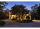 Elegant home exterior featuring a circular driveway, manicured landscaping, and beautiful lighting at dusk at 11201 Jonas Ridge Ln, Raleigh, NC 27613