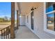 Covered porch featuring wooden pillars, a black front door, and exterior lighting at 1178 Sheriff Johnson Rd, Lillington, NC 27546