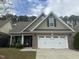 Two-story home with a white double garage door and landscaping at 166 Easy Wind Ln, Garner, NC 27529