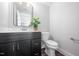 Stylish half-bathroom with a dark vanity, a potted plant, and hardwood floors at 313 E Fourth St, Wendell, NC 27591