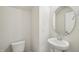 Contemporary half-bath with a pedestal sink and round mirror offers a convenient space at 911 Montague Ave, Durham, NC 27703