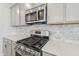 Close up of a modern kitchen with stainless steel appliances and light gray marbled backsplash at 913 Montague Ave, Durham, NC 27703