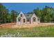 Striking new construction featuring a light brick facade, gabled roof, and energy-efficient windows set against a lush treeline at 1117 Delilia Ln, Wake Forest, NC 27587