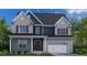 Two-story home with gray brick and blue siding, a three-car garage, and a covered front porch at 3201 Armeria Dr, Apex, NC 27502