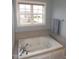 Close up of a jetted tub with a window view and a neutral tile surround in the bathroom at 35 Meadow Ln, Franklinton, NC 27525