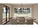 Bright dining room with a wooden table set, modern lighting, and large windows overlooking a green landscape at 403 Carolyn Ct, Cary, NC 27511