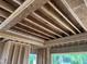 Under-construction living room with open ceilings featuring wood beams and natural light from multiple windows at 403 Carolyn Ct, Cary, NC 27511