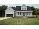 Charming two-story home boasts a welcoming front porch, attached garage, and a lush green lawn at 404 Brodie Rose Landing Way, Smithfield, NC 27577