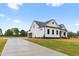 Exterior angle view of a modern farmhouse-style home with a lush green yard and long driveway at 541 Delma Grimes Rd, Coats, NC 27521