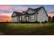 Dusk view of the white farmhouse-style home showcasing modern design and manicured lawn at 541 Delma Grimes Rd, Coats, NC 27521