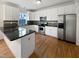 L-shaped kitchen with white cabinets, granite counters, and stainless steel appliances at 5621 Voorhees Ln, Holly Springs, NC 27540