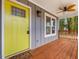 Close-up of a charming front porch with a bright yellow door and wood flooring at 624 S Eighth St, Mebane, NC 27302