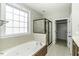 Bright bathroom featuring a bathtub, shower with glass, and closet access, complemented by tiled floors at 1201 Rivermead Ln, Wake Forest, NC 27587