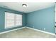 This carpeted bedroom features a large window and fresh blue paint at 1201 Rivermead Ln, Wake Forest, NC 27587