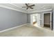 Bedroom with gray walls, tray ceiling, ceiling fan, carpet, and open access to an ensuite bathroom and closet at 1201 Rivermead Ln, Wake Forest, NC 27587