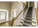 Inviting home foyer with a staircase with carpet runner and a window seat with natural light at 1201 Rivermead Ln, Wake Forest, NC 27587