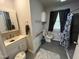 Bathroom features white vanity, toilet, and shower with gray tile surround and blue floral shower curtain at 2612 Academy St, Sanford, NC 27332