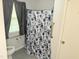 Bathroom featuring a shower/tub combination with a floral shower curtain and gray tile at 2612 Academy St, Sanford, NC 27332