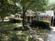 Charming red brick home with a covered porch, mature trees, and lush landscaping at 2612 Academy St, Sanford, NC 27332